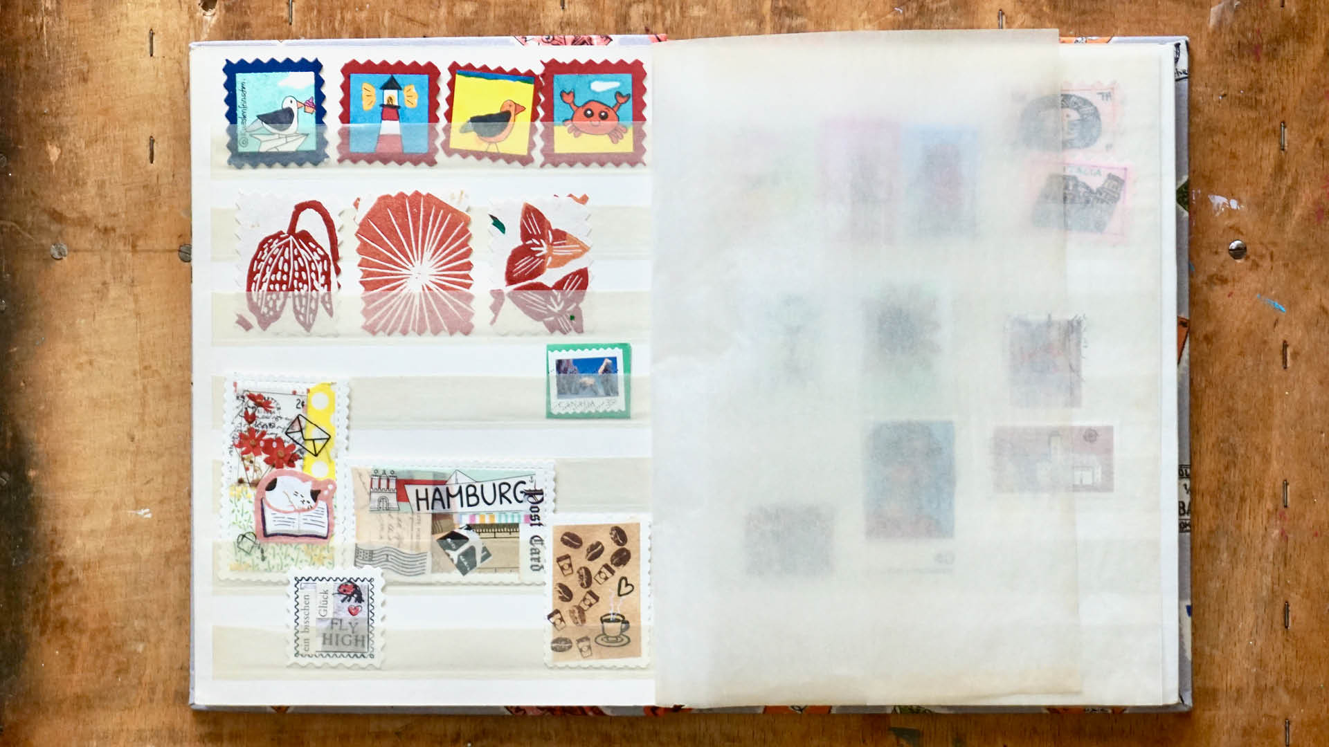 geöffnetes Briefmarken-Sammelalbum mit selbstgemachten bunten Briefmarken