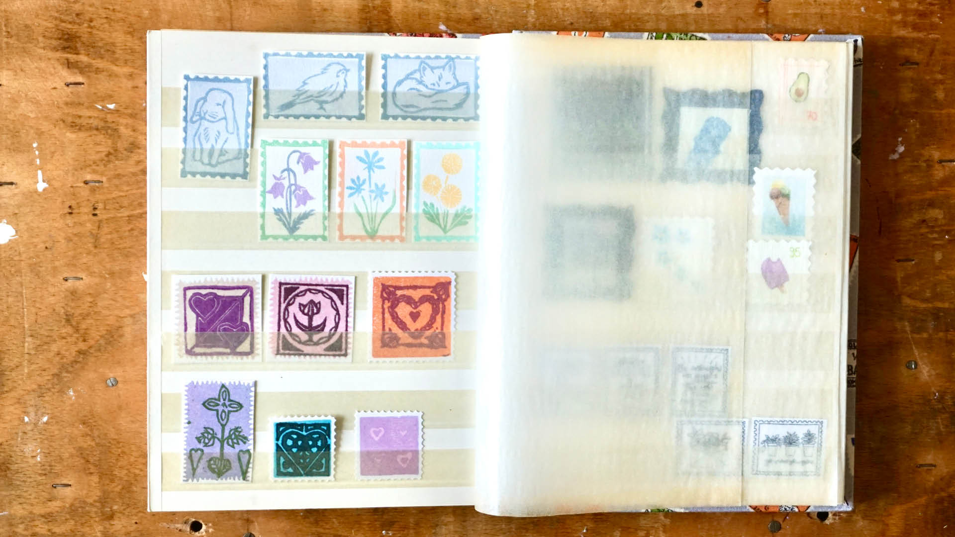 Geöffnetes Briefmarkenalbum mit selbstgemachten, bunten Briefmarken