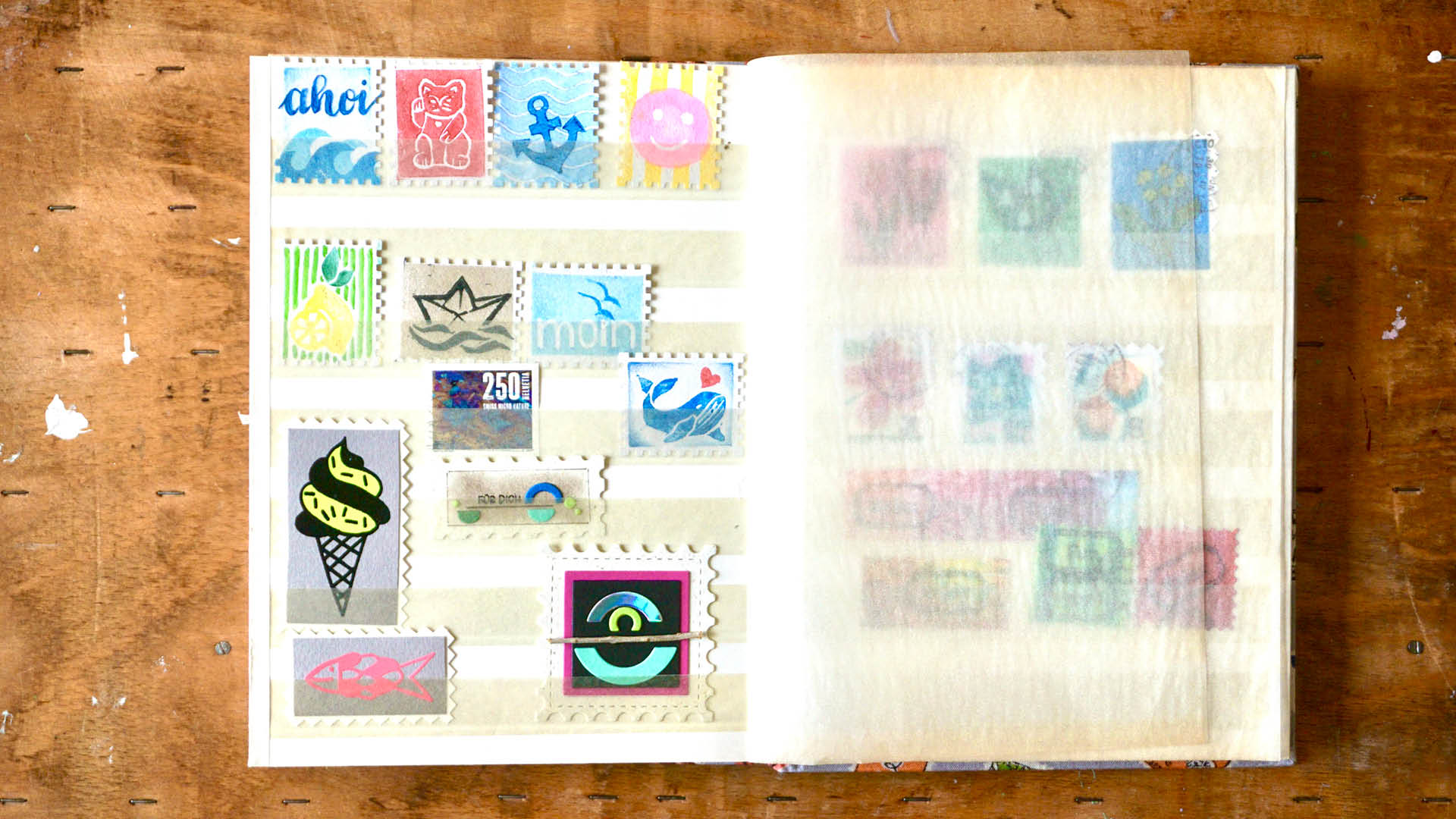 Geöffnetes Briefmarkenalbum mit selbstgemachten, bunten Briefmarken