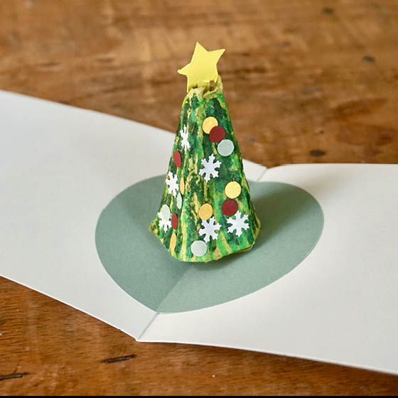 Als Weihnachtsbaum dekorierte Spitze steht inmitten der geöffneten Karte
