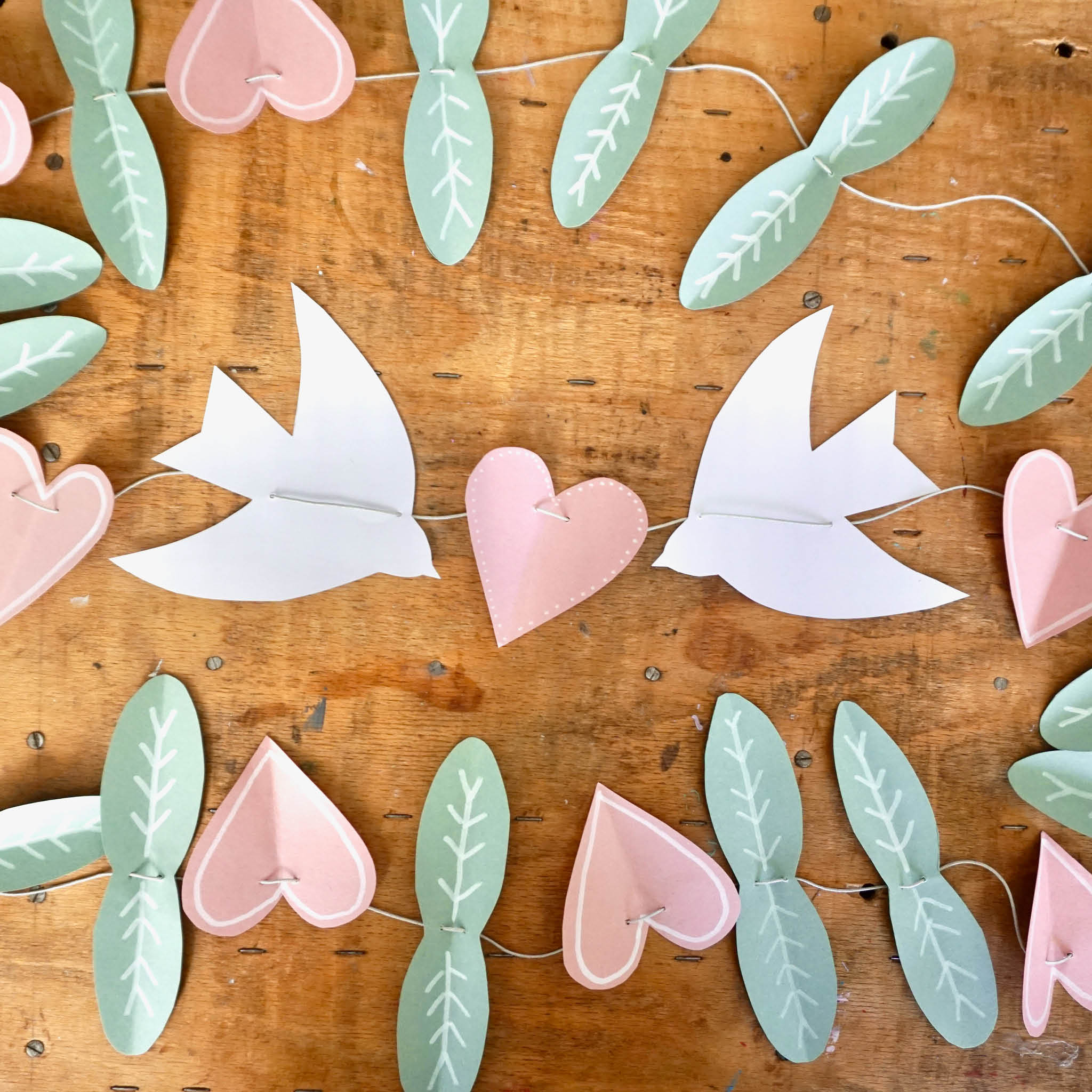 DIY Frühlingsgirlande: ausgeschnittene Blätter, Herzen und Vögel auf einer Schnur