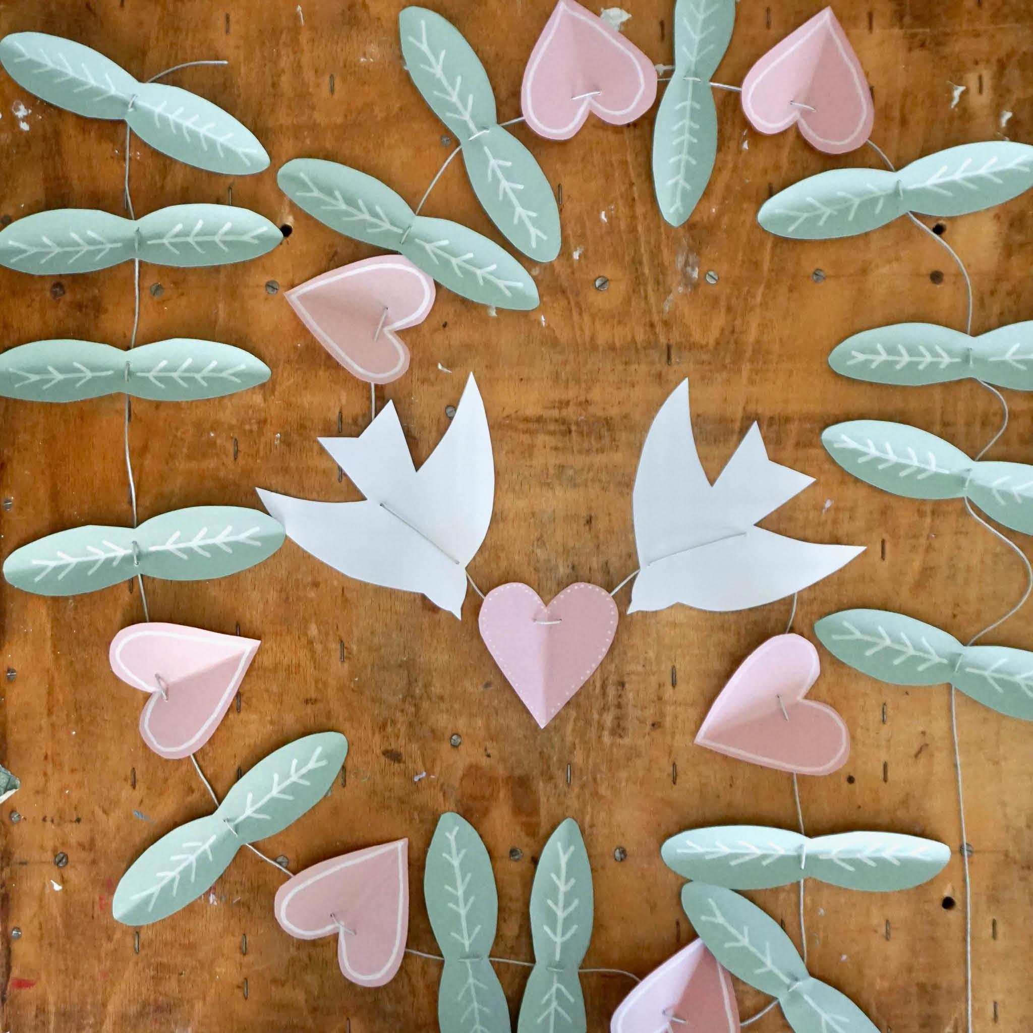 DIY Frühlingsgirlande: ausgeschnittene Blätter, Herzen und Vögel auf einer Schnur