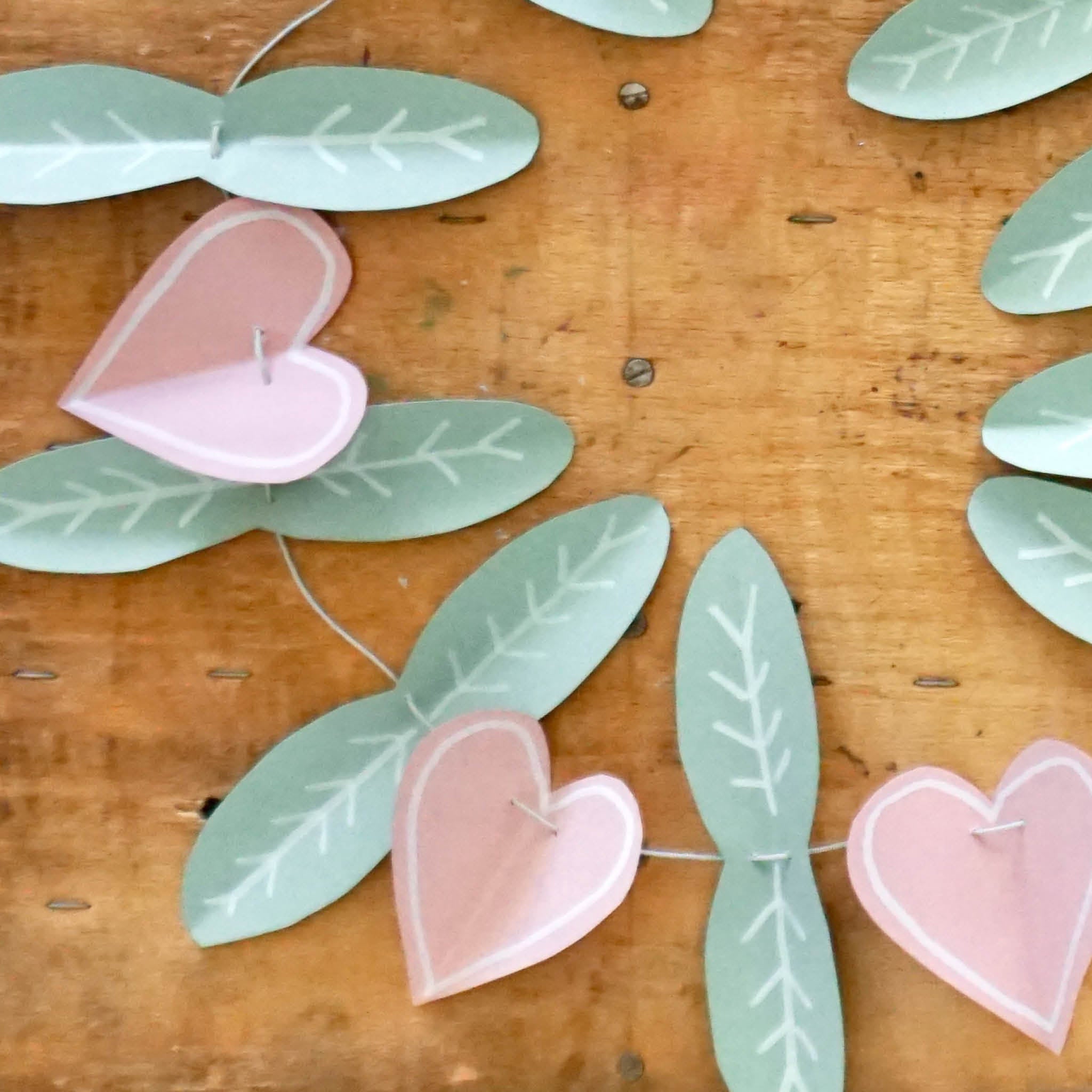 DIY Frühlingsgirlande: ausgeschnittene Blätter, Herzen und Vögel auf einer Schnur - Nahaufnahme