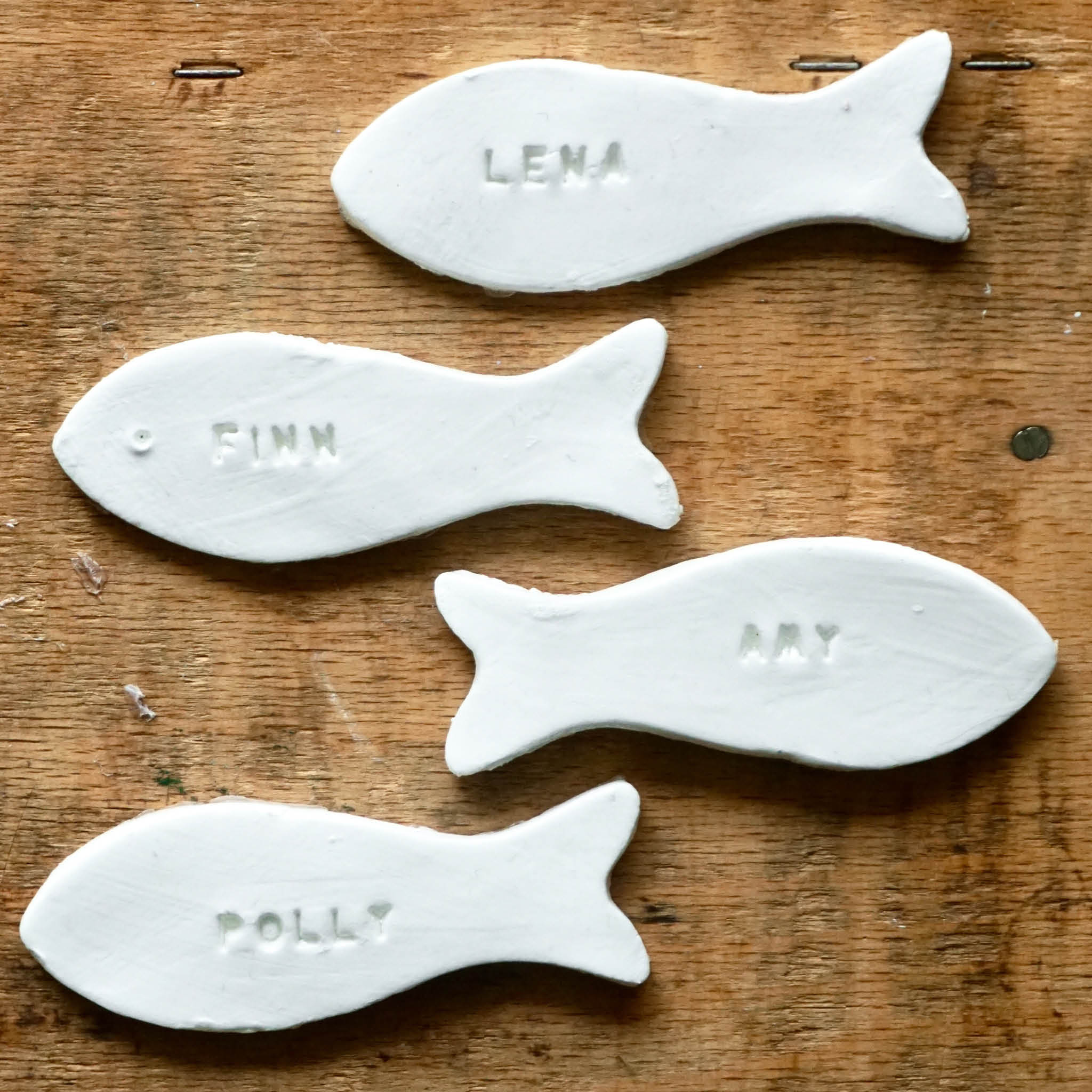Platzkarten aus Modelliermasse in Fischform - 4 Beispiele: Weiße Fische mit eingestempelten Namen