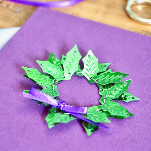 Weihnachtskarte zum Selberbasteln "Gloria" - lila Karte mit Kranz aus grünen Ilex-Pailletten - Beispie-Karte, Nahaufnahme